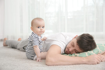 father fall asleep with cute baby daughter on carpet at home