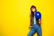 © dianagrytsku - Cheerful excited hipster girl in red hat holding balloon on yellow wall