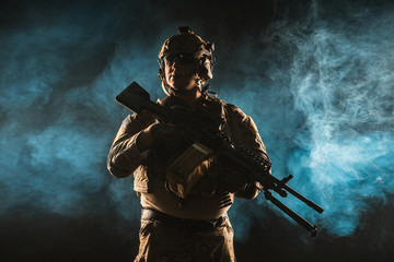 Sticker - Army soldier in Combat Uniforms with machine gun, plate carrier and combat helmet are on. Studio contour silhouette shot, backlight, dark glowing smoke background