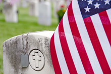 Military Dog Tags And American Flag On Veteran's Tombstone