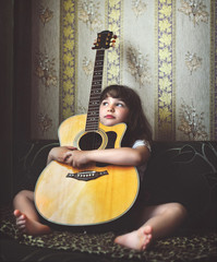 Little girl hugging an acoustic guitar.