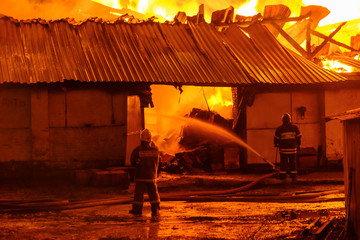 Wall Mural - Firefighters extinguish a fire in a burning warehouse