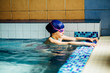© Iryna - Happy cute little girl wearing blue swimming cap in a pool
