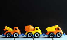 Line Of Plastic Colorful Toy Trucks Against The Black Background