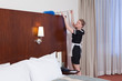 © Connect Images - room maid dusting bed, laughing