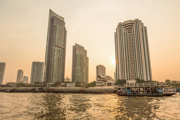 Wall Mural - BANGKOK, THAILAND, MARCH 02, 2017 - Chao Praya River in Bangkok, buildings and boats at sunset