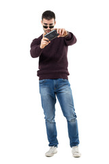 Wall Mural - Concentrated young casual man taking picture with mobile phone. Full body length portrait isolated over white studio background.