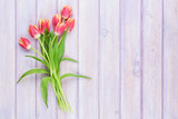 Fototapeta Tulipany - Red tulips over purple wooden table