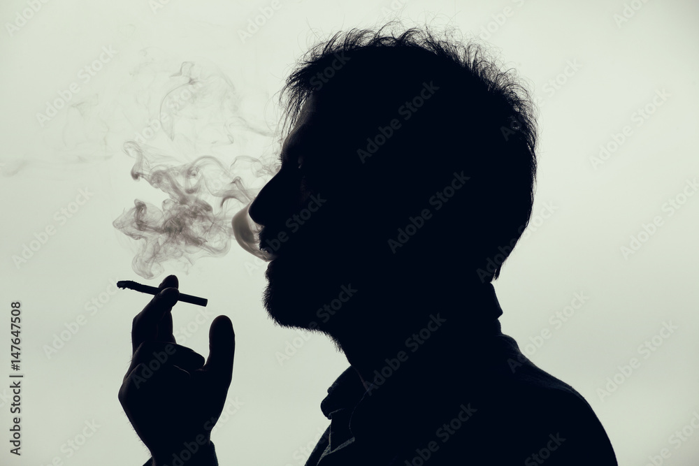 cigarette silhouette Man smoking a cigarette. Silhouette Stock Photo
