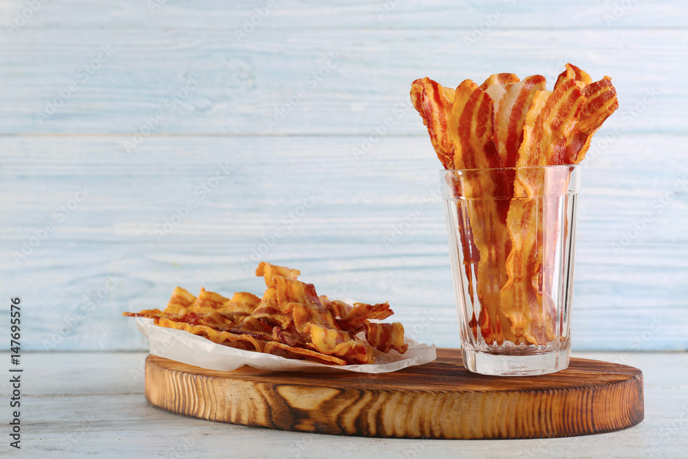 Tasty bacon slices on wooden board