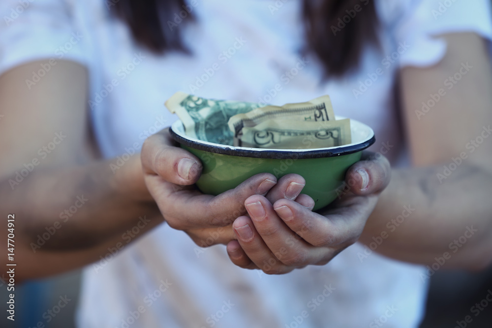 Poor woman holding bowl with money
