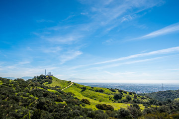 Wall Mural - Green grass and blue sky on a mountainside with hiking trails and power tower.