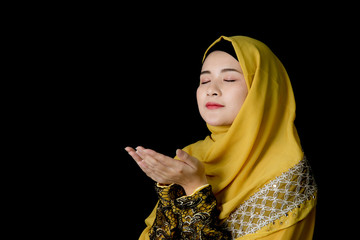 religious young Muslim woman praying over black background.