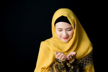 religious young Muslim woman praying over black background.