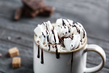 Poster - Cup of cocoa with whipped cream, marshmallows and chocolate syrup on wooden table