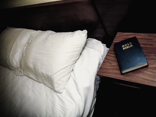 Holy Bible Nightstand Motel Room. Motel room bed with a bible on a the night stand.