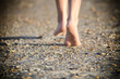 Young child walking barefoot on sandy beach with shells