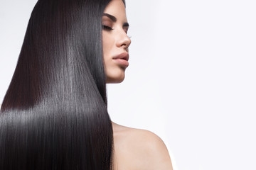 Beautiful brunette girl in move with a perfectly smooth hair, and classic make-up. Beauty face. Picture taken in the studio on a white background.