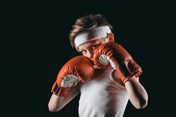 Wall Mural - boy obscuring face with boxing gloves isolated on black, active kids concept