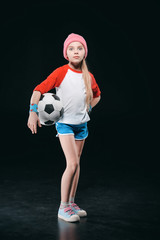 Wall Mural - Cute girl in sportswear posing with soccer ball isolated on black, activities for children concept