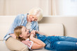 Happy grandmother and granddaughter having fun together on sofa