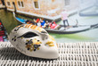 Authentic mask from Venice with a gondolier and tourists in gondola in the background. Golden souvenir and traditional Venetian boat in the world famous canal. Sunny summer travelling in Italy.