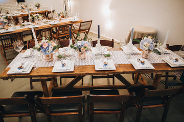 Wall Mural - The wooden festive table is decorated with compositions of flowers, candles and served with cutlery, glasses and plates