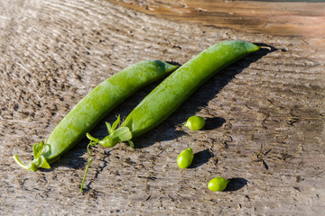 Fresh green pods and peas on a wooden background