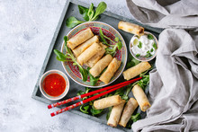 Fried Spring Rolls With Red And White Sauces, Served In China Plate On Wood Tray With Fresh Green Salad And Wooden Chopsticks Over Gray Blue Texture Background. Flat Lay, Space. Asian Food