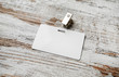Blank white plastic badge on vintage wooden table background. Blank plastic id card. Selective focus. Top view.