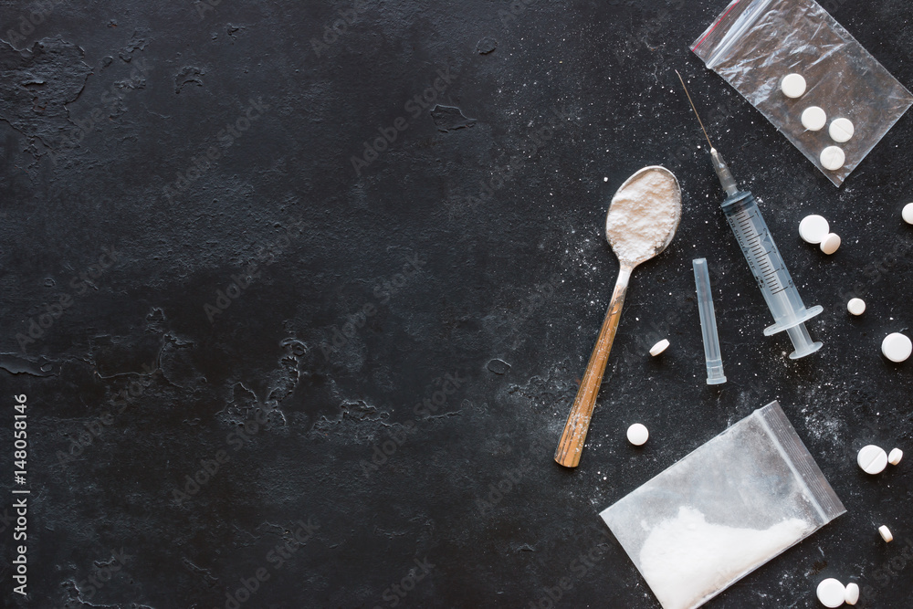 Drugs in the form of powder and tablets, a spoon and a syringe on a black background mockup - obrazy, fototapety, plakaty 
