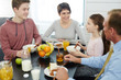 © pressmaster - Profile view of cute little girl telling something to her family while eating cornflakes with milk, her father in formalwear, pretty mother and teenage brother listening to her with interest