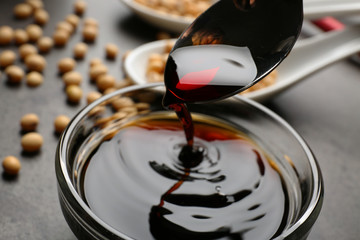 Wall Mural - Bowl with tasty soy sauce and spoon on table, closeup