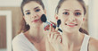 © shefkate - Beautiful girls looking in the mirror and applying cosmetic with a big brush