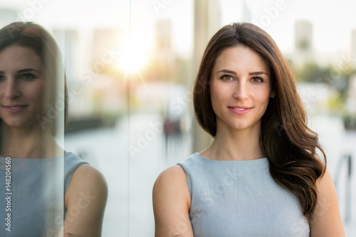 Fotografie, Obraz Casual portrait of a beautiful brunette model as sunset on city skyline in backg
