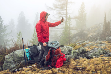 Wall Mural - hiker travels in the mountain forest in the mist with a backpack and trying to find a mobile connect