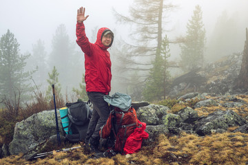 Wall Mural - hiker travels in the mountain forest in the mist with a backpack welcomes all friends