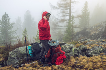 hiker travels in the mountain forest in the mist with a backpack and trying to find a mobile connect
