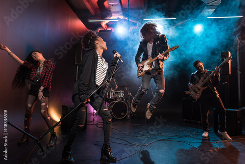Obraz Dibond Młody wieloetniczny zespół rock and rollowy wykonujący hard rock na scenie