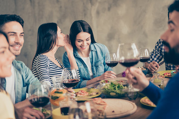 Close up of two girls gossipping at the party. Friends are celebrating together with drinks and tasty food