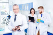 © deagreez - Teamwork in lab. Close up focused portrait of professor in lab coat and glasses holding tablet and looking serious and concentrated