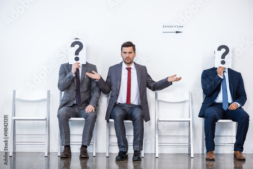 Fotografie, Obraz businesspeople sitting in queue and waiting for interview, holding question mark