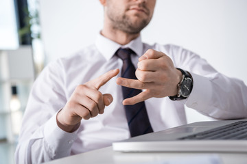 partial view of businessman counting on fingers at workplace, business concept