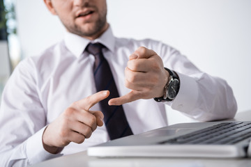partial view of businessman counting on fingers at workplace, business concept