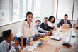 © Monkey Business - Businesswoman Stands To Address Meeting Around Board Table
