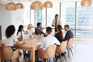 Poster - Businessman Stands To Address Meeting Around Board Table