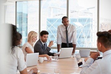 Wall Mural - Businessman Stands To Address Meeting Around Board Table