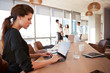 © Monkey Business - Businesswoman Uses Laptop As Colleagues Meet In Background