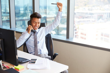 Wall Mural - Celebrating Businessman Making Phone Call At Desk In Office