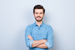 © deagreez - Close up portrait of cheerful brunet young man in jeans shirt crossing hands and look at camera on lifgt background